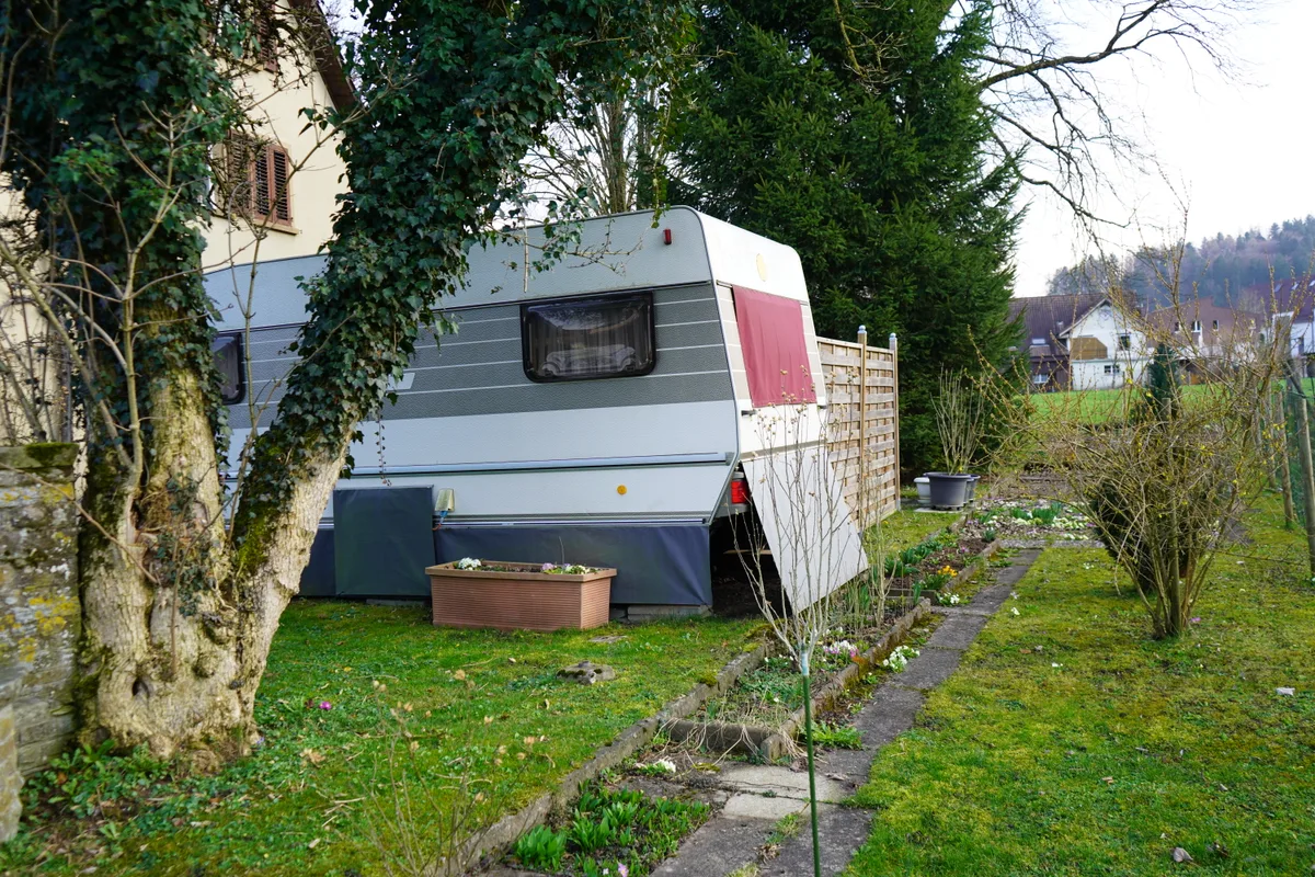 Ein Garten mit Wohnwagen und kleinen Blumenbeeten,